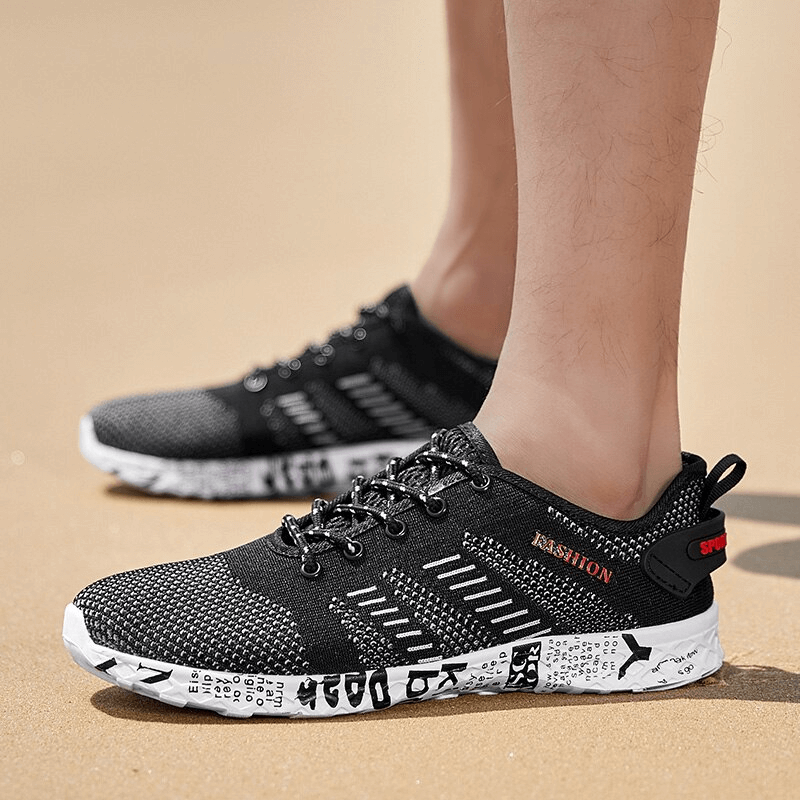 Men's casual black lace-up mesh sneakers with geometric pattern, shown outdoors, featuring soft outsole and breathable design for comfort.